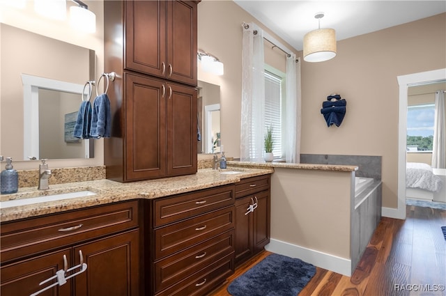 bathroom featuring double vanity, baseboards, a sink, and wood finished floors