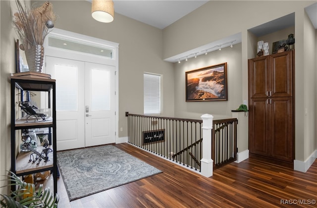 foyer entrance with dark wood-style floors, rail lighting, baseboards, and french doors