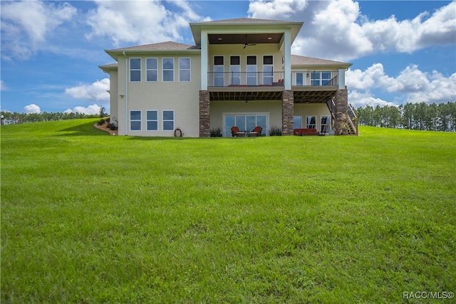 rear view of property featuring a ceiling fan, stucco siding, a lawn, and stairs