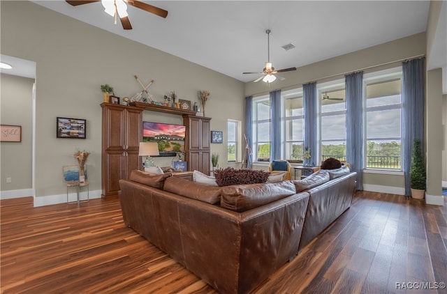 living room with dark wood-style floors, visible vents, baseboards, and a ceiling fan