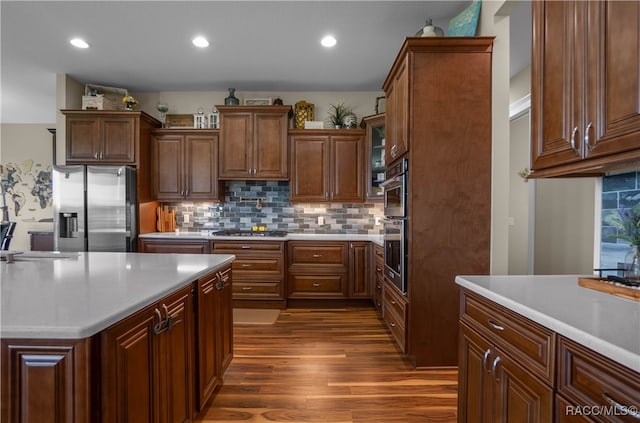 kitchen featuring stainless steel appliances, dark wood-type flooring, light countertops, and decorative backsplash