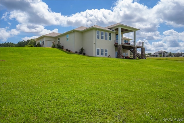 back of house with a garage, a lawn, stairway, a deck, and stucco siding