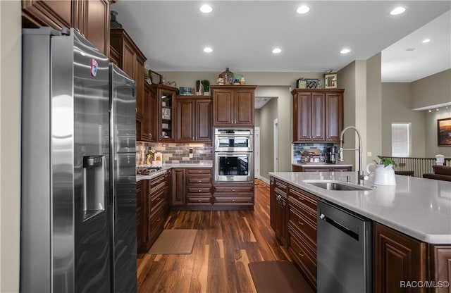 kitchen with appliances with stainless steel finishes, dark wood-style flooring, light countertops, a sink, and recessed lighting