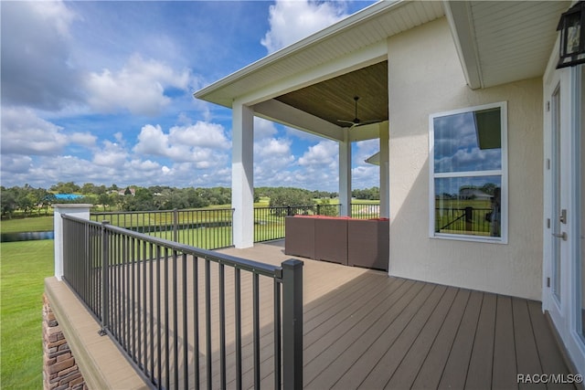 wooden terrace featuring a ceiling fan and a lawn