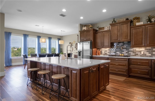 kitchen with a sink, visible vents, light countertops, appliances with stainless steel finishes, and decorative backsplash