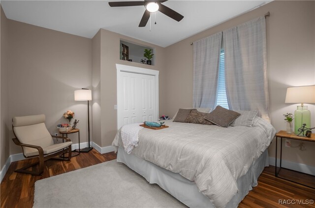 bedroom with a closet, ceiling fan, baseboards, and wood finished floors