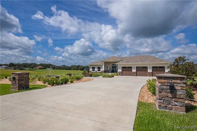 view of front facade with driveway, stone siding, and an attached garage