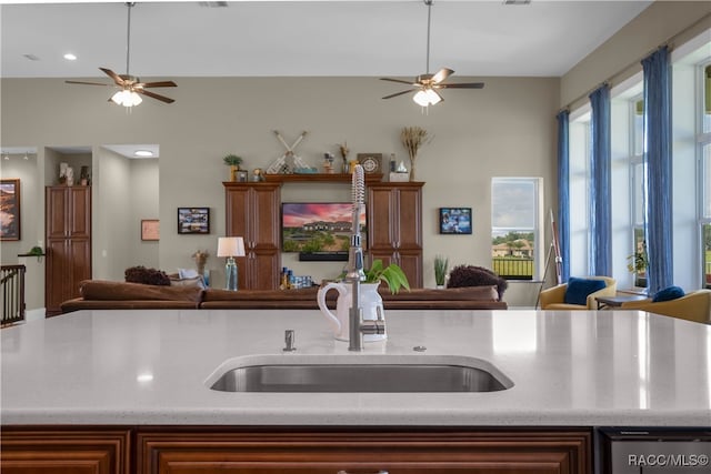 kitchen featuring visible vents, light stone counters, open floor plan, and a sink