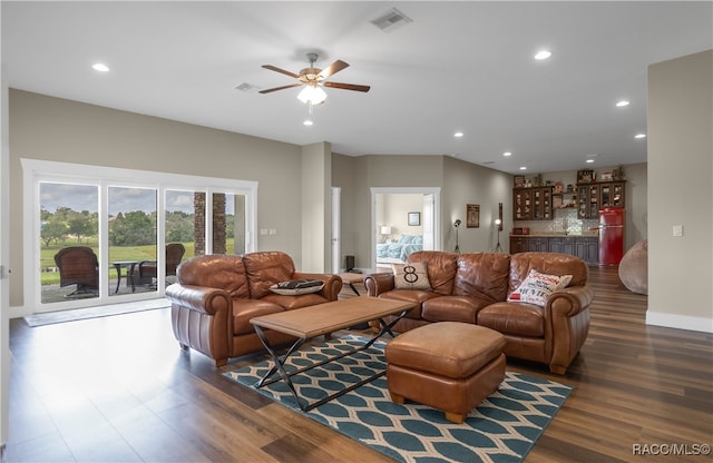 living room featuring dark wood-type flooring, recessed lighting, visible vents, and a dry bar