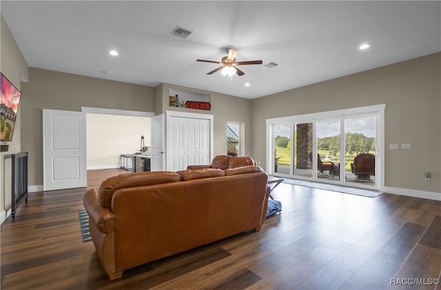 living area featuring dark wood-style flooring, visible vents, and baseboards