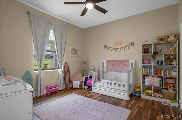 bedroom featuring ceiling fan, a crib, and wood finished floors