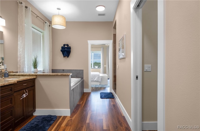 full bath with visible vents, plenty of natural light, vanity, and wood finished floors