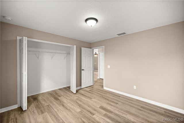 176 Juniper Loop Cir, Ocala, FL 34480 - unfurnished bedroom with light wood-type flooring, baseboards, a closet, and a textured ceiling