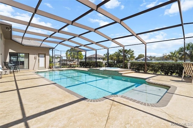 view of pool with a patio area, glass enclosure, and a pool with connected hot tub