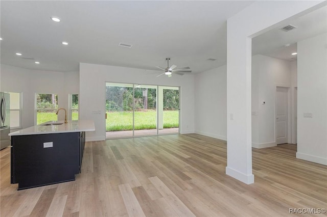 unfurnished living room with sink, ceiling fan, and light hardwood / wood-style flooring