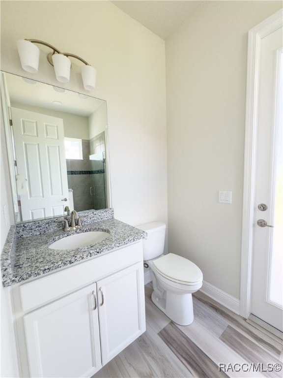 bathroom featuring hardwood / wood-style floors, vanity, toilet, and a shower with door