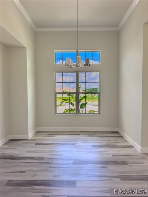 unfurnished dining area with light hardwood / wood-style flooring, an inviting chandelier, and ornamental molding