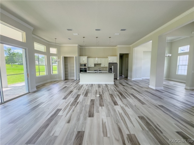 unfurnished living room featuring sink, light wood-type flooring, and crown molding