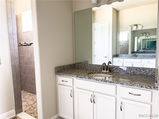 bathroom featuring a tile shower and vanity