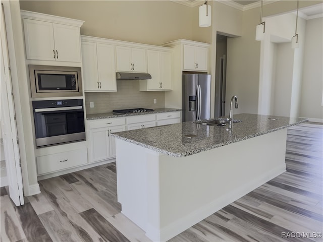 kitchen with stone counters, white cabinetry, sink, stainless steel appliances, and a center island with sink