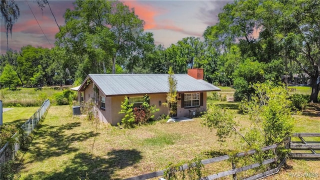 8915 E Echo Ct, Inverness, FL 34450 - view of front of house with stucco siding, a chimney, metal roof, and view of scattered trees