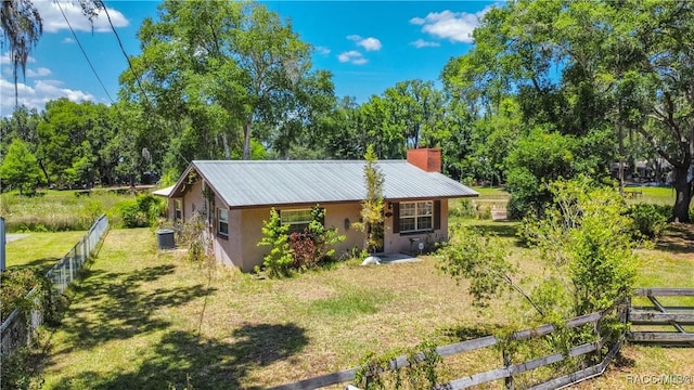 8915 E Echo Ct, Inverness, FL 34450 - view of side of home featuring stucco siding, a chimney, metal roof, and central AC unit