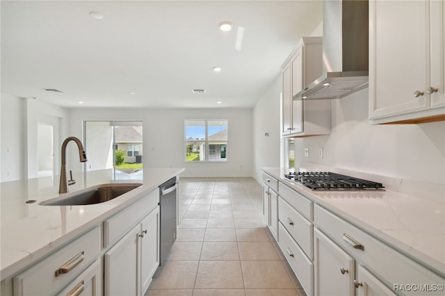 kitchen with sink, white cabinets, wall chimney range hood, and appliances with stainless steel finishes