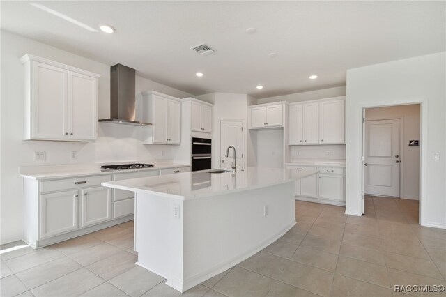 kitchen with white cabinets, a kitchen island with sink, and wall chimney exhaust hood