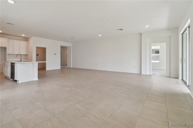 unfurnished living room featuring light tile patterned floors and sink