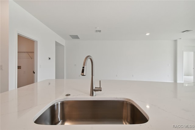 interior details featuring light stone countertops and sink