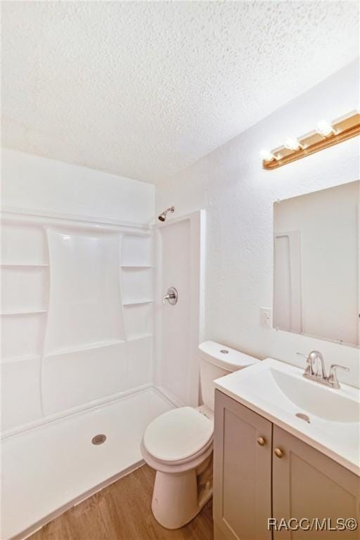 bathroom with toilet, hardwood / wood-style flooring, a textured ceiling, a shower, and vanity