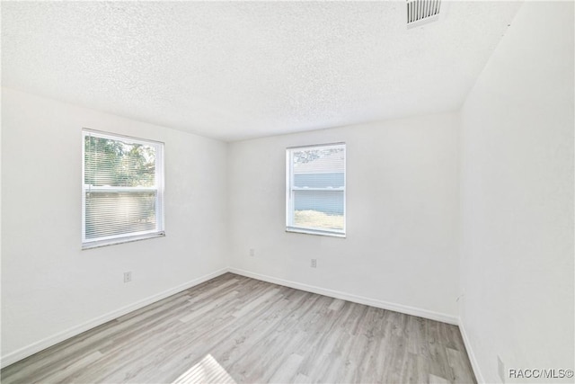 spare room with a textured ceiling and light hardwood / wood-style floors