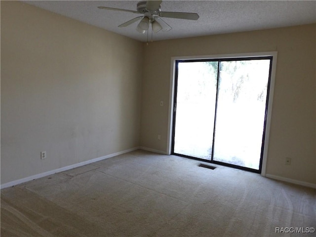 empty room featuring ceiling fan, light colored carpet, and a textured ceiling