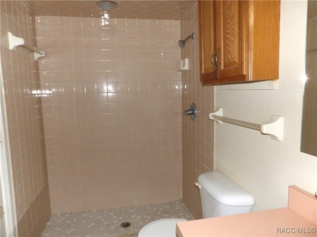 bathroom with a tile shower and toilet