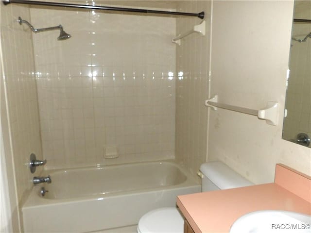 full bathroom featuring vanity, tiled shower / bath combo, and toilet