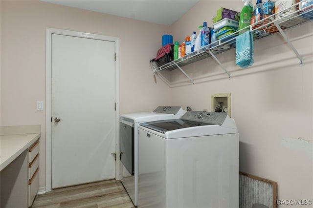 clothes washing area with washer and dryer and light hardwood / wood-style flooring