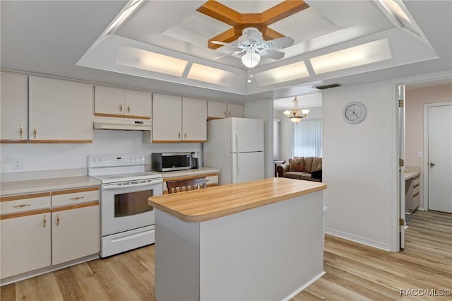 kitchen with light hardwood / wood-style floors, a kitchen island, white appliances, and a tray ceiling