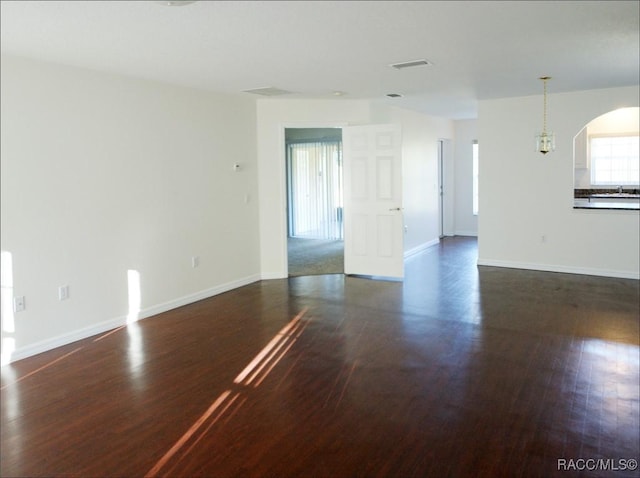 spare room with dark hardwood / wood-style floors and a chandelier