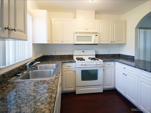 kitchen with dark hardwood / wood-style flooring, white appliances, sink, dark stone countertops, and white cabinetry