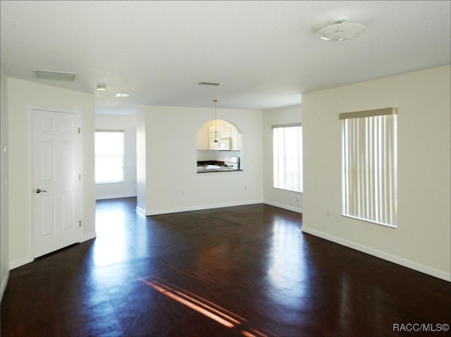 empty room with dark hardwood / wood-style flooring and plenty of natural light