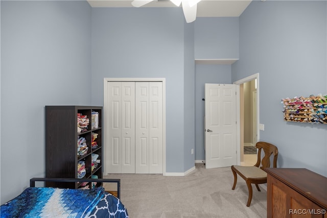 carpeted bedroom with ceiling fan, a towering ceiling, and a closet