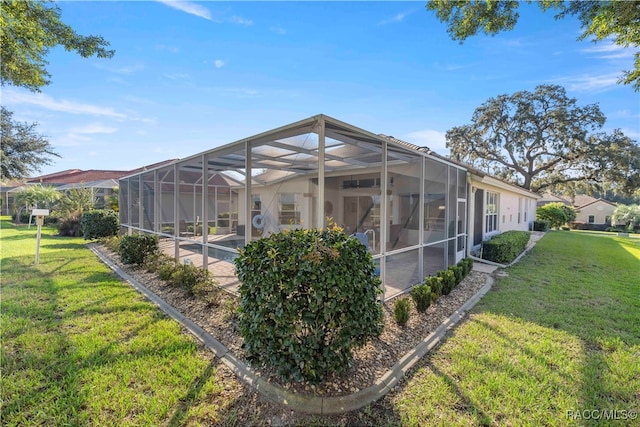 rear view of house with a lanai and a yard