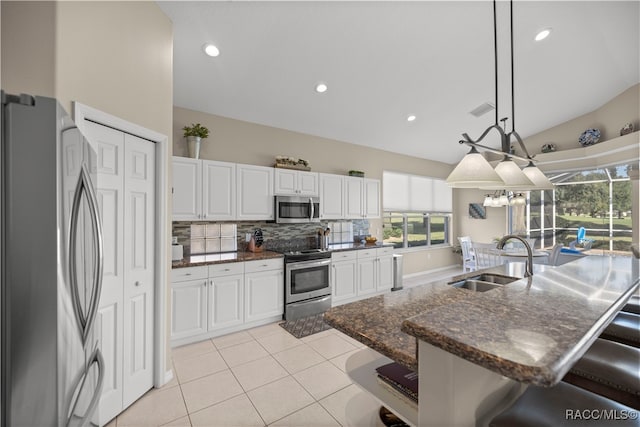 kitchen featuring a kitchen breakfast bar, stainless steel appliances, sink, white cabinetry, and hanging light fixtures