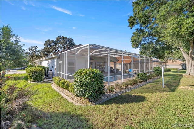 rear view of property featuring a lanai and a yard