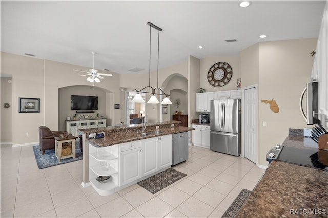 kitchen featuring pendant lighting, dark stone counters, an island with sink, appliances with stainless steel finishes, and white cabinetry