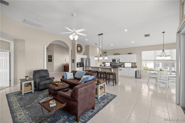 living room with ceiling fan with notable chandelier and light tile patterned floors