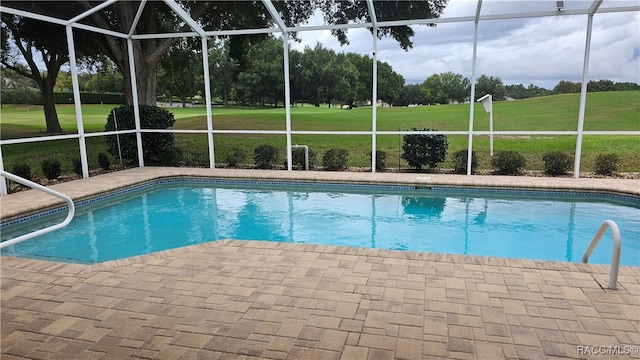 view of pool with a lawn, a patio area, and a lanai