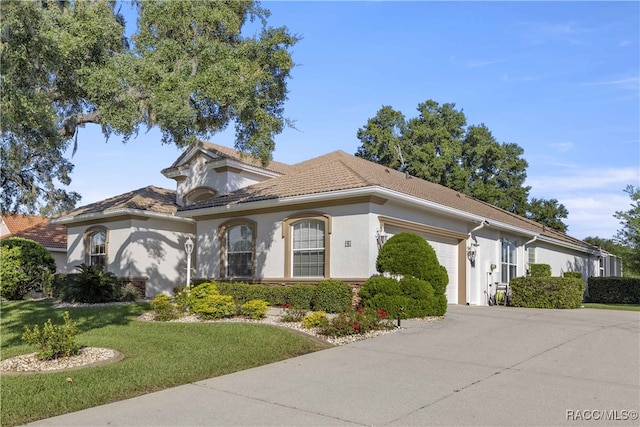 mediterranean / spanish home featuring a front yard and a garage