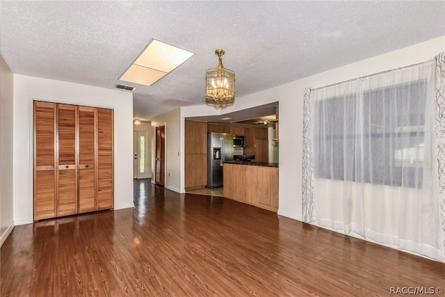 unfurnished living room featuring a textured ceiling and dark hardwood / wood-style floors