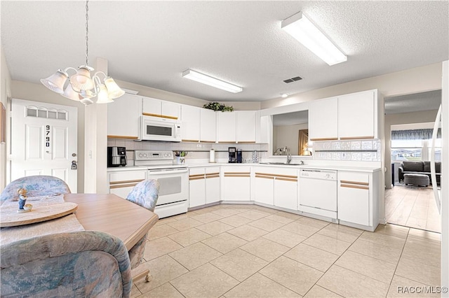 kitchen with a textured ceiling, light tile patterned floors, white cabinets, and white appliances